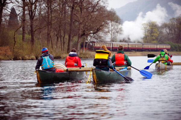 A group of people wearing life jackets while canoeing down a river.