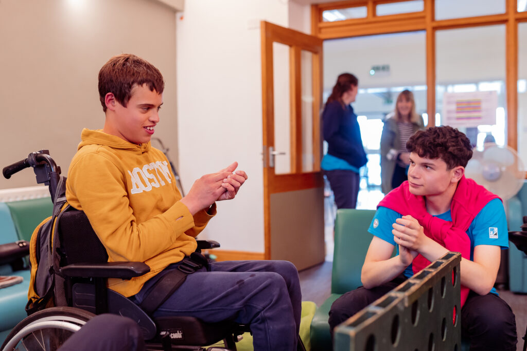 2 people sitting and talking in the lounge whilst playing connect 4